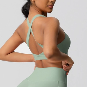 Détail des bretelles croisées du soutien-gorge de sport vert et du legging de yoga taille haute