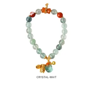 Detailed view of strawberry crystal beaded bracelet with green jade and gold bell charms