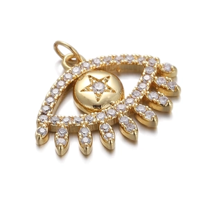Macro view of gold evil eye pendant with clear zircons and engraved star detail