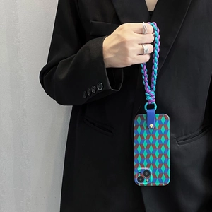 Detail of a geometric pattern phone case with a blue woven lanyard held by a model
