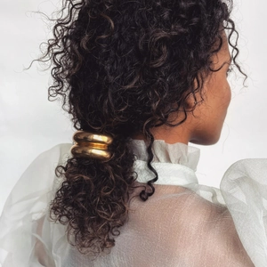 Macro view of thick golden metal hair cuff styled on a low ponytail hair tie