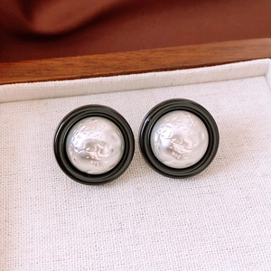 Close-up of vintage round stud earrings with silver hammered texture and black border