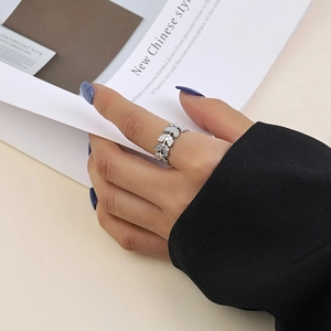 Bague feuille en argent avec zircons portée au doigt avec costume et magazine élégant