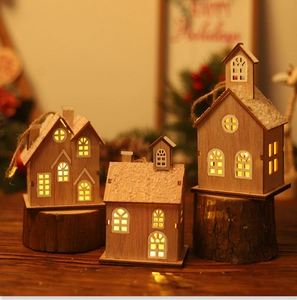 Macro detail of LED glowing wooden Christmas house ornaments with faux snow and twine