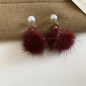 Detailed view of burgundy flocking pony earring with white pearl and soft fur ball