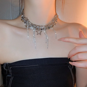 Close-up of a silver multilayered star necklace with rhinestone tassels on model's neck