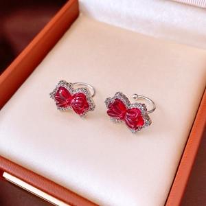 Macro view of sparkly zircon bow ear clips with red resin finish and silver metal base