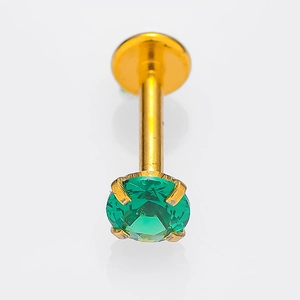 Dettaglio macro del piercing per labbra in titanio dorato con zircone verde e base piatta