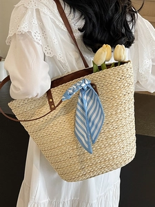 Minimalist straw tote bag with leather straps and striped scarf for beach vacation style
