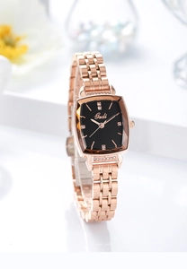 Close-up of rose gold tonneau-shaped watch with rhinestone bezel and black dial