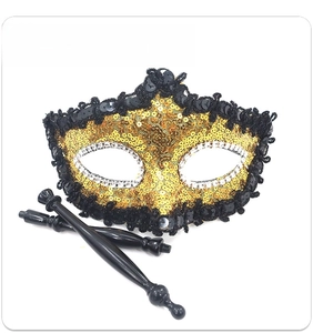 Detail of masquerade mask featuring gold sequins and detachable hand-held sticks