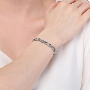 Gros plan d'un bracelet en chaîne torsadée argentée avec fermoir rotatif porté au poignet