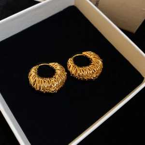 Détail macro de boucles d'oreilles créoles plaquées or 18 carats au design torsadé
