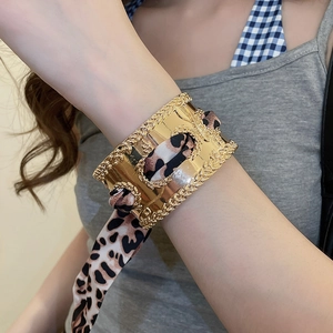 Detail of gold-plated open cuff bracelet with leopard print silk scarf weaving detail