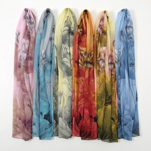 Lightweight chiffon floral scarves in six gradient colors hanging against white wall