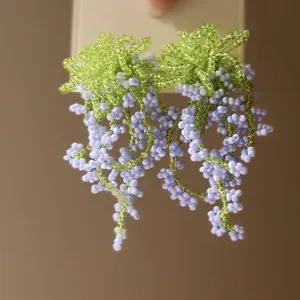 Detail of handmade beaded fringe earrings featuring green and purple wisteria floral drops