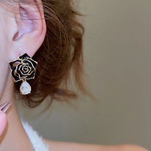 Detailed view of black rose earrings with teardrop zircon on woman's earlobe