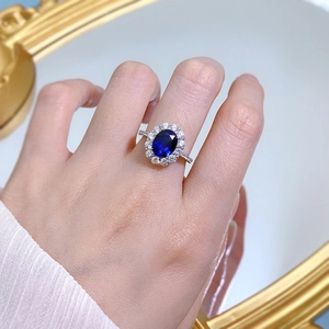 Macro view of oval blue sapphire ring with halo diamonds on a silver band