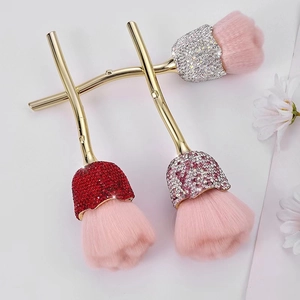 Three rose-themed makeup brushes with gold branch handles and rhinestone crystal bases