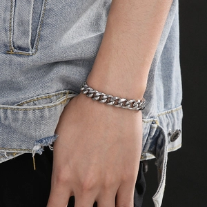Close-up of polished silver stainless steel Cuban link bracelet worn on a male wrist