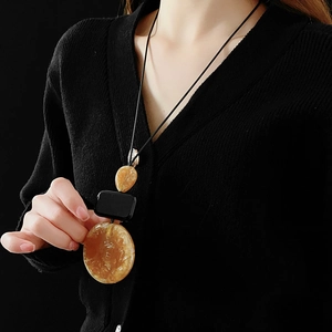 Detail of a brown resin geometric drop necklace on model with minimalist retro aesthetic