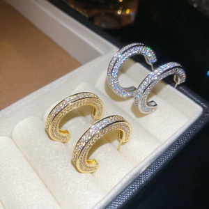 Close-up of gold and silver C-shaped earrings with micro-pave zircons in a jewelry box