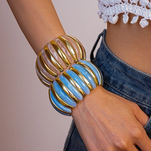Macro shot of wide textured gold cuffs with blue and white resin inlays on a model