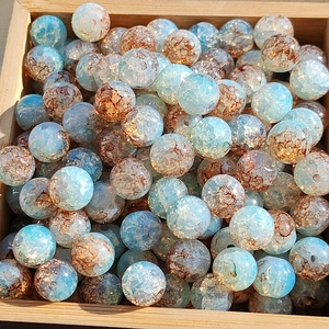 Macro view of blue and amber cracked glass beads with gold foil effect in a wooden tray