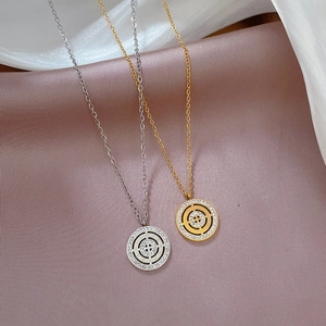 Detail of gold and silver titanium necklaces with crystal-rimmed round pendants on silk