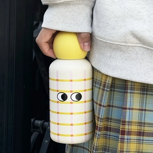 Close-up of a 350ml stainless steel thermos with creative cartoon eyes and grid pattern
