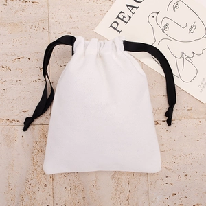 Close-up of white canvas drawstring pouch with black ribbon on stone texture