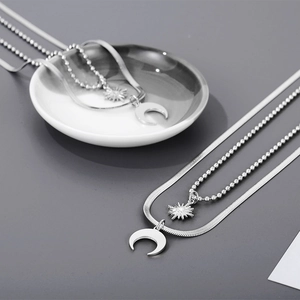 Detail of silver double-layered snake and bead chain necklace with sun and moon pendants