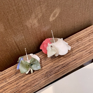Artistic multi-color floral resin earrings displayed on natural wooden base