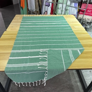 Detail view of green and white striped Turkish beach towel with elegant white woven fringes
