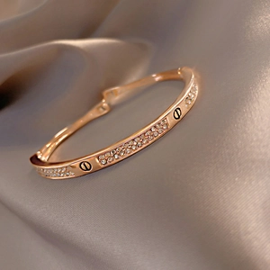 Macro shot of rose gold double-row pavé diamond bangle with circular screw motifs
