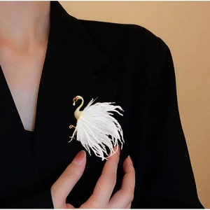 Detail of elegant swan brooch with white feathers and gold metal on a black suit blazer