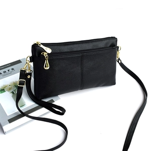 Detailed macro view of black lychee-textured leather crossbody bag with golden zippers