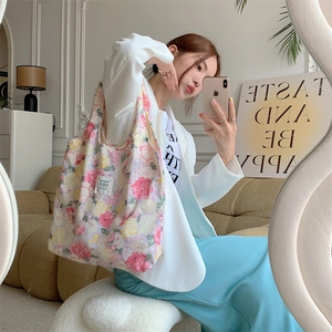 Borsa tote in tela a fiori mostrata in un selfie con blazer bianco e vestito blu