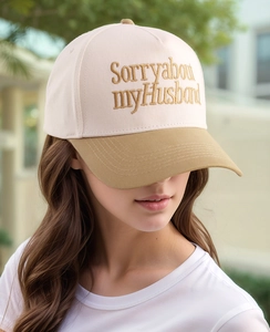 Detail der Sorry about my Husband Goldbestickung auf zweifarbiger Trucker Baseballkappe