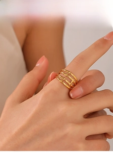 Detail of gold-plated multi-layer hollow ring worn on finger showing minimalist design