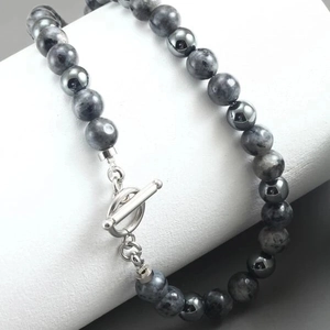Detail of beaded necklace featuring black stone beads and a silver-toned metal T-bar toggle clasp