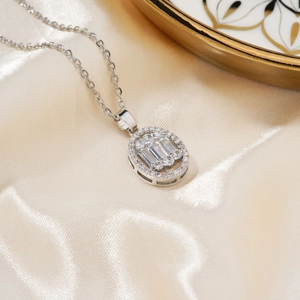 Elegant silver oval halo necklace with baguette crystals on champagne satin fabric