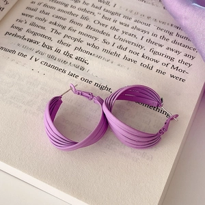 Detail of purple matte twisted hoop earrings with silver needles on vintage book page