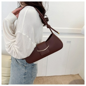 Detail of a dark brown baguette bag with golden buckle and knotted shoulder strap detail