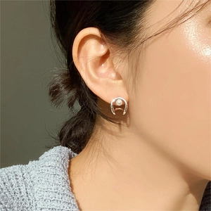 Close-up of minimalist 925 silver horseshoe earring with a white lustrous pearl inlay