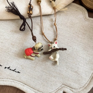Close-up of cute ceramic kitten and puppy pendants on woven cords with wooden beads