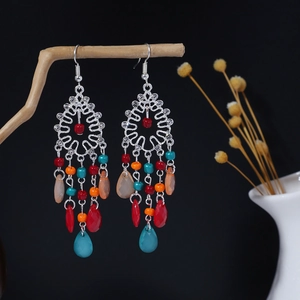 Dettaglio di orecchini boho con nappe, perline colorate e ciondoli a goccia traslucidi