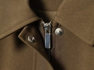 Close-up of metal zipper and snap button on brown bomber jacket textile fabric