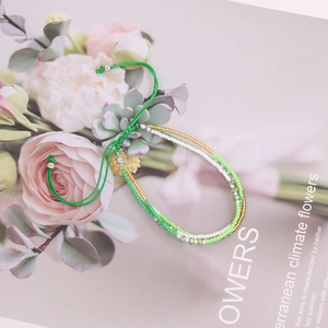 Detailed view of handmade green and white seed bead woven bracelet on floral background