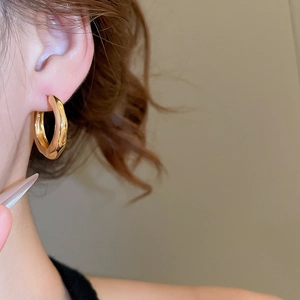 Close-up of 18K gold plated wrinkled C-shape earring showing texture on a model's ear